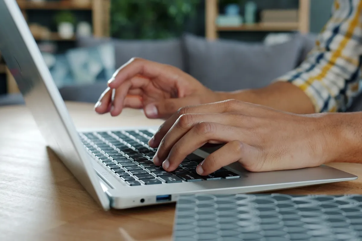 Hands typing a message on a laptop keyboard at a desk
